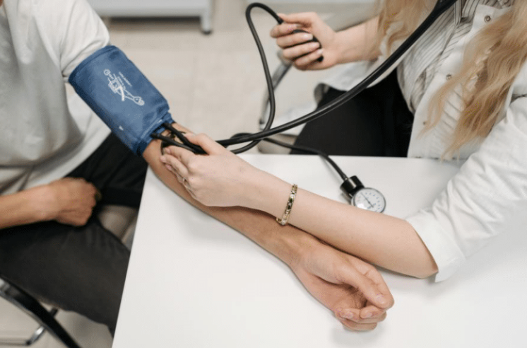 Photo of a person having a blood pressure test. The person has an inflatable cuff on their arm which is linked to a pressure gauge and air pump.
