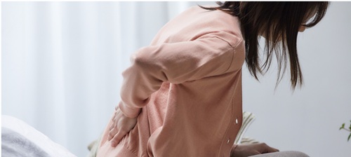 Woman holder her back as if in pain