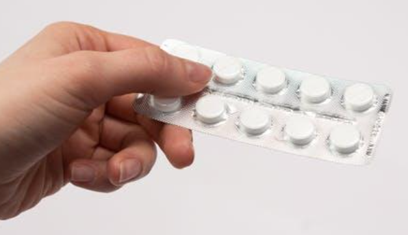 A person holding a packet of tablets.