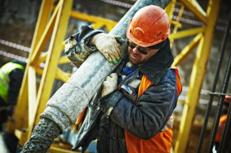 A photo of a labourer laying cement on a building site