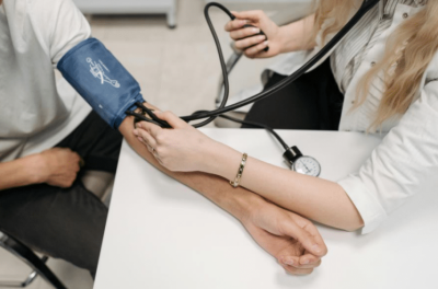 Photo of a person having a blood pressure test. The person has an inflatable cuff on their arm which is linked to a pressure gauge and air pump.