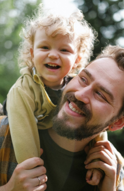 Picture of father holding a toddler on his shoulders.