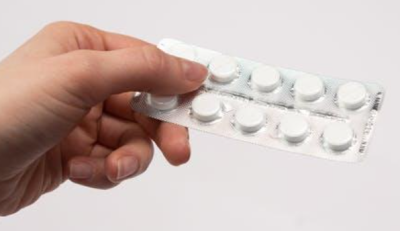 A person holding a packet of tablets.