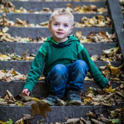 A picture of a young boy sitting on steps outdoors.