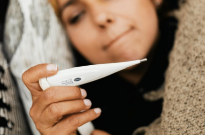 Picture of a woman looking at a thermometer.